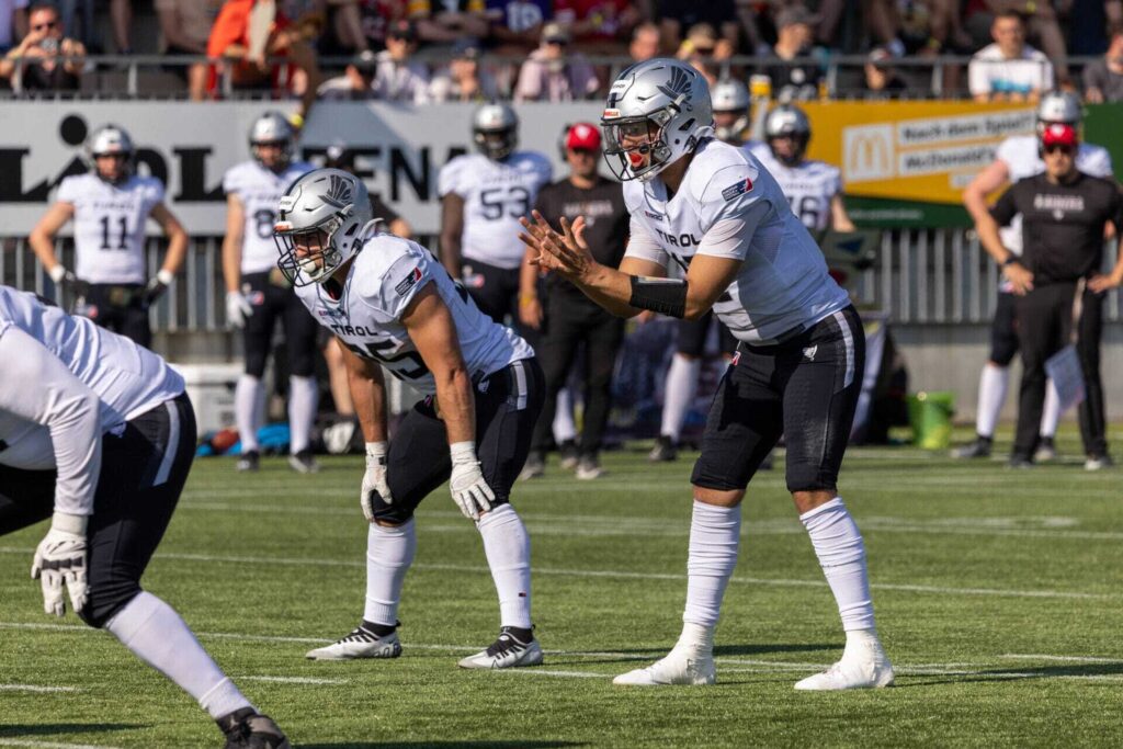 Football players in formation on a green field during a game.