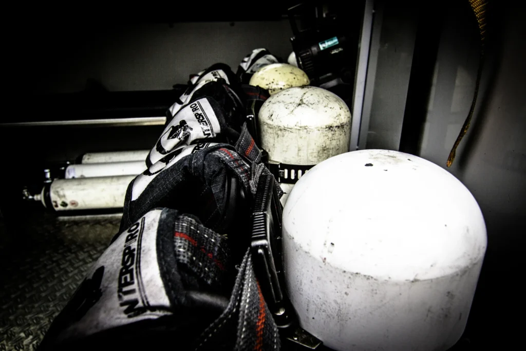Firefighter oxygen tanks and gear including Interspiro mask, in fire truck compartment.