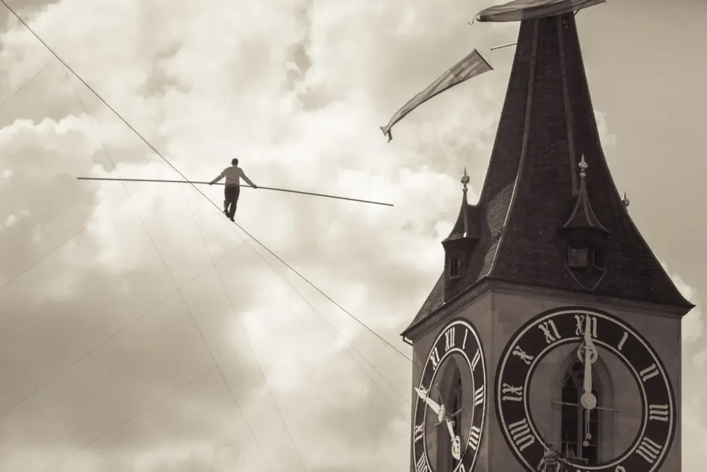 Monochrome image of a high wire walker near Zurich clock tower.