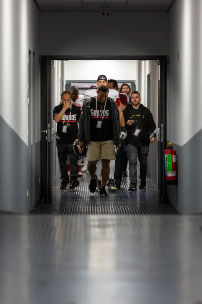Football team walks down tunnel, focused and determined, ready to compete.