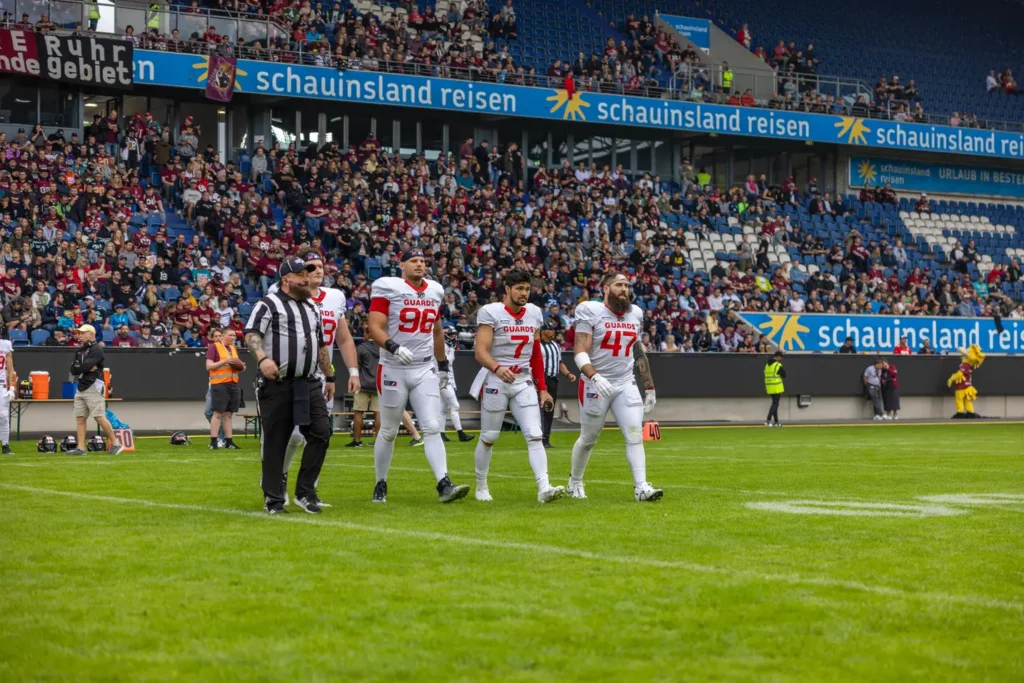 American football players and referee on a vibrant green football field.