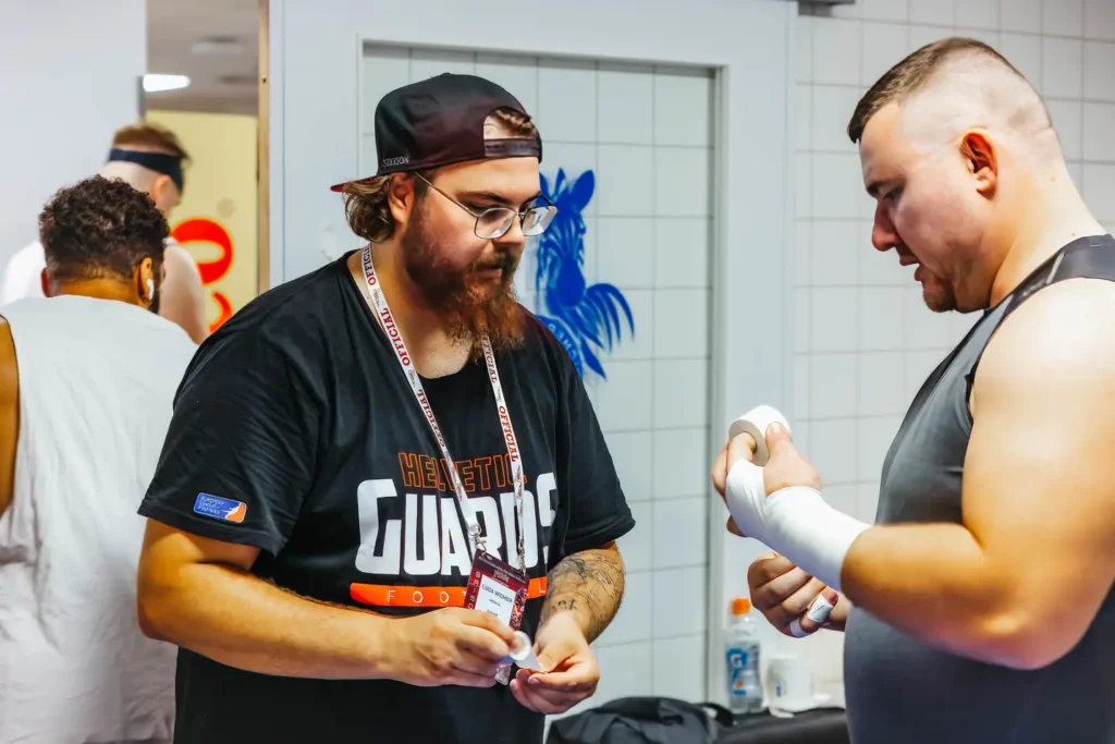 Football athlete getting his hand and wrist wrapped with white athletic tape.