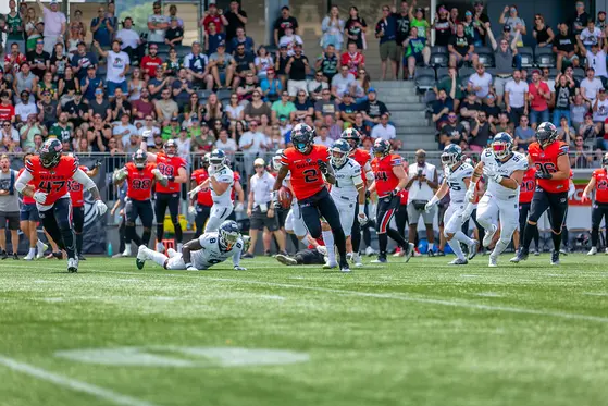 American football player in action, running with the ball during a game.