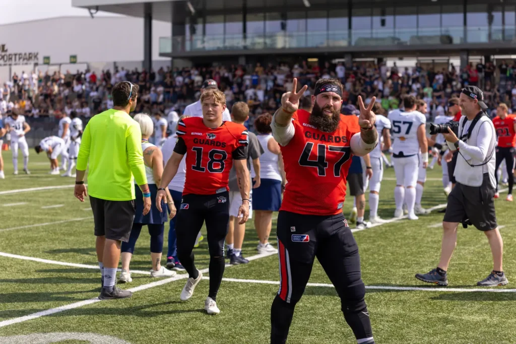 Two football players in red jerseys celebrating a victory with peace signs.