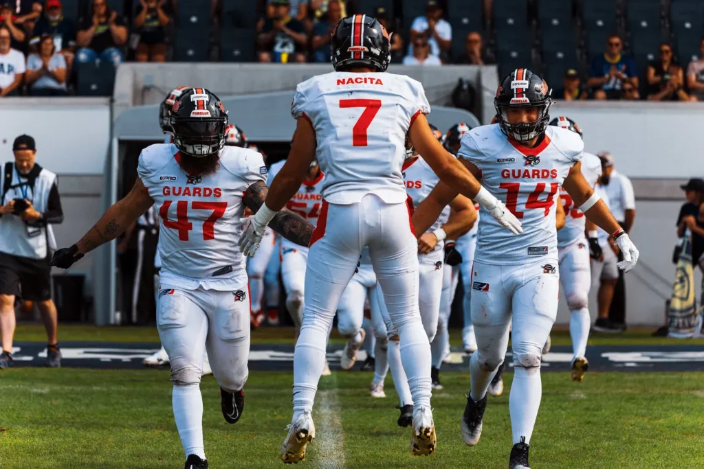 Football team running onto field, white uniforms, focus on energy.