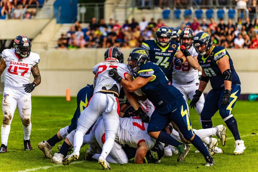 American football players clashing during a game; action shot, intense moment.