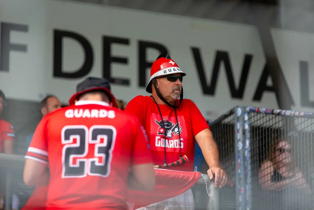 Football fan in a Swiss Guards helmet watching game
