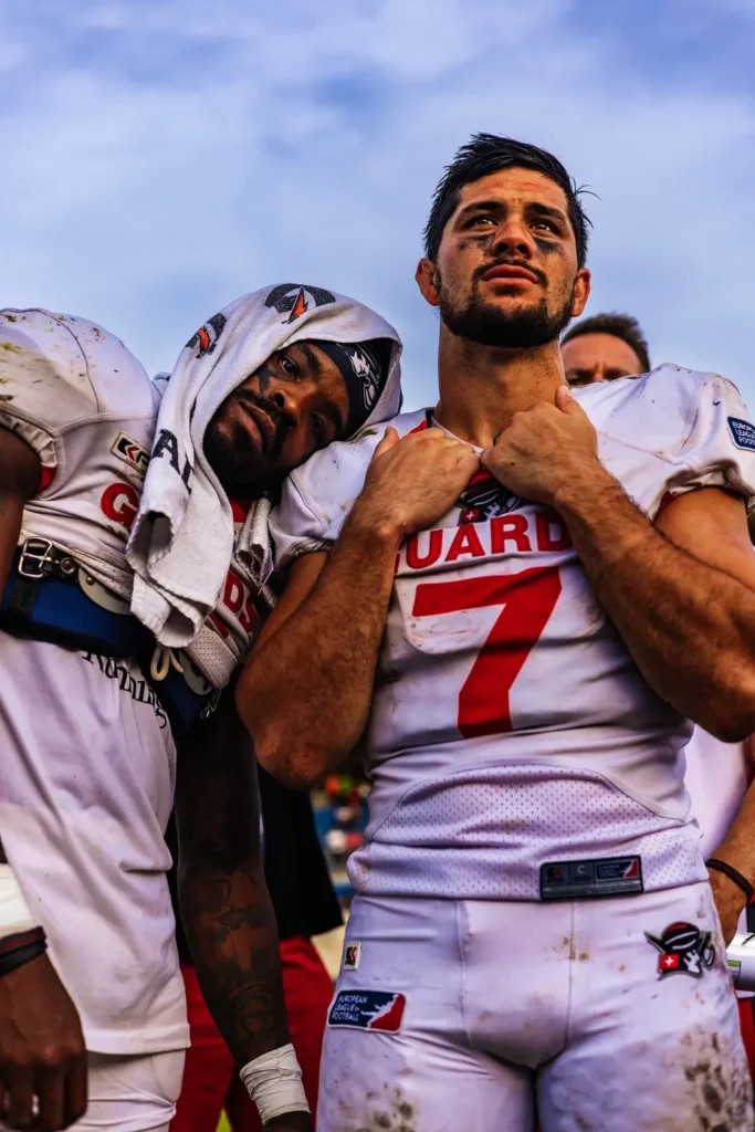 Two exhausted football players lean on each other after a game.