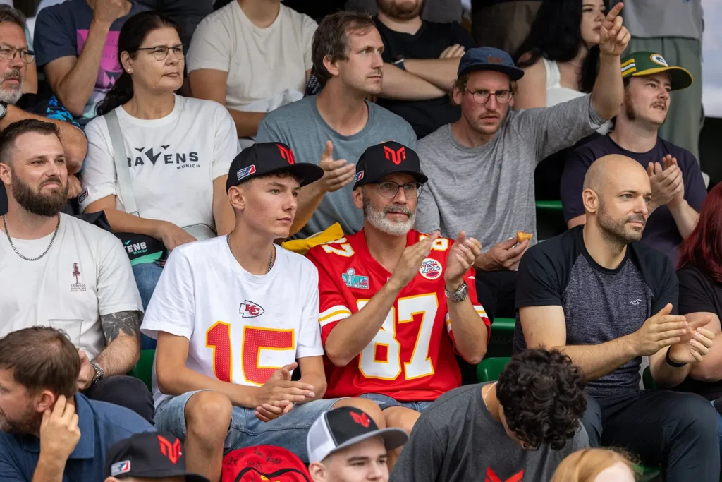 Fans in jerseys watch a game, supporting the Kansas City Chiefs.