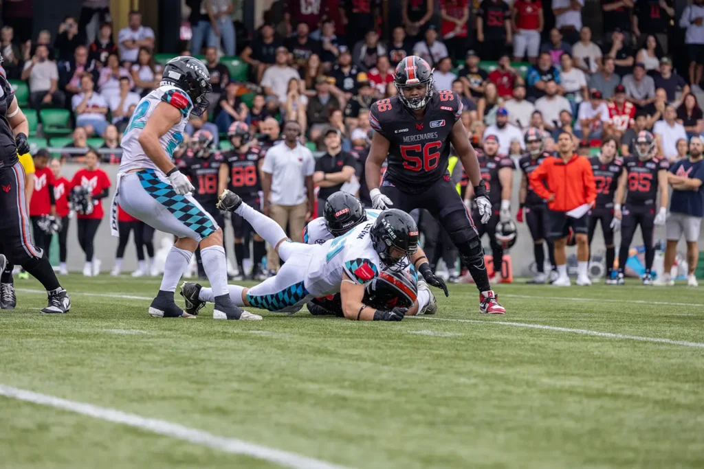 Football players tackle on the field in a competitive game.