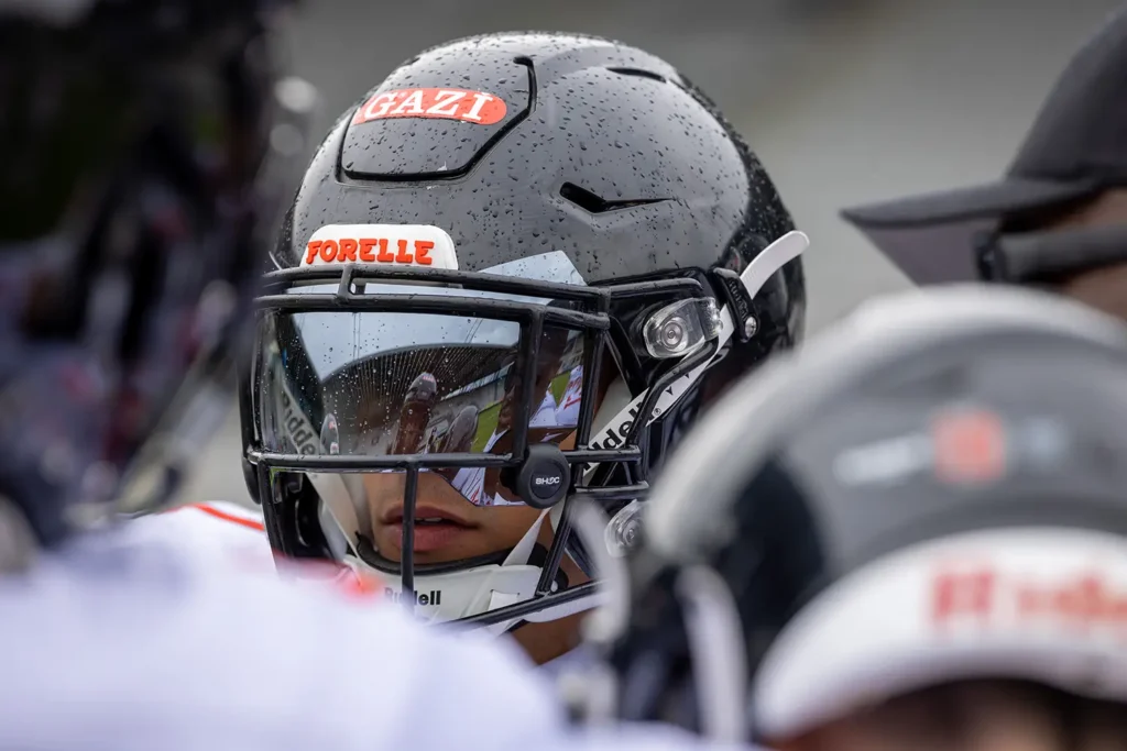 Close-up of football player wearing helmet with stadium reflection in visor.