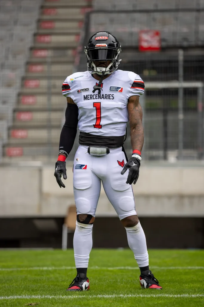 Football player in white uniform with helmet and pads, ready for action.