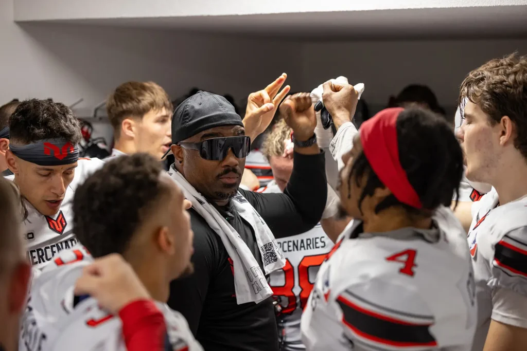 Football coach in huddle with players before game, intense energy