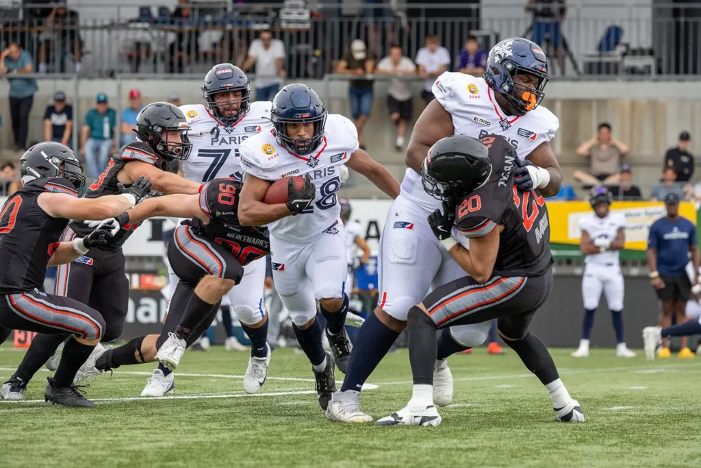 Football player running with ball, defenders close, intense game action.