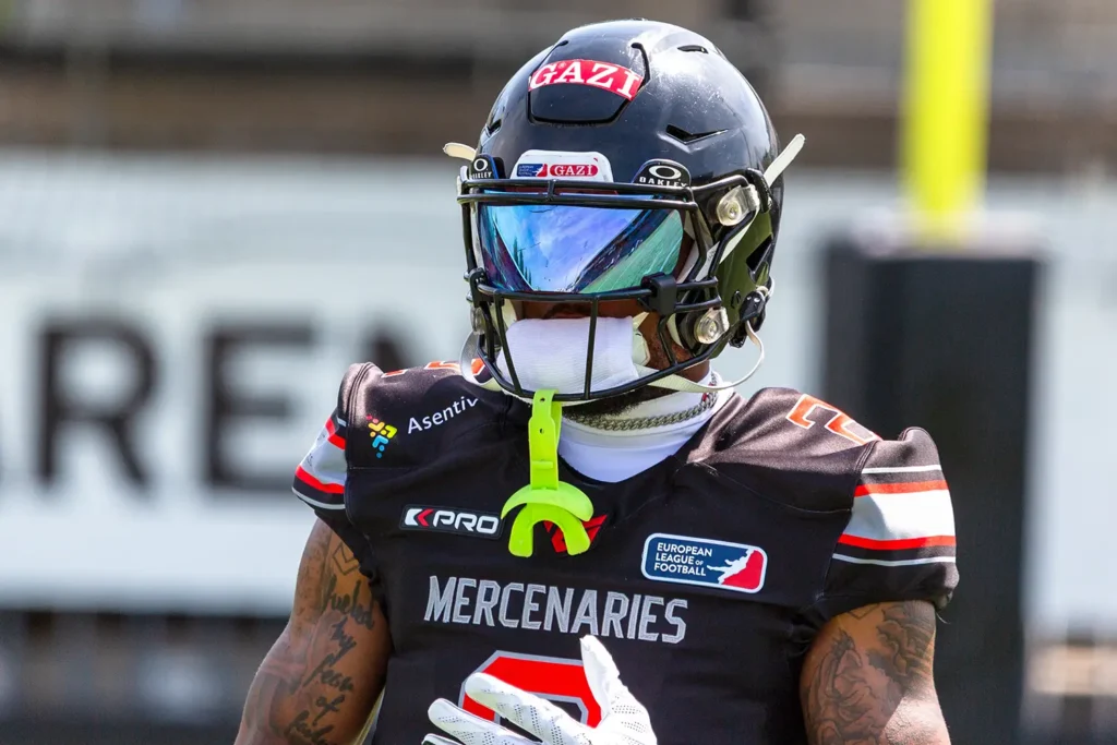 Football player in black uniform with helmet and reflective visor.