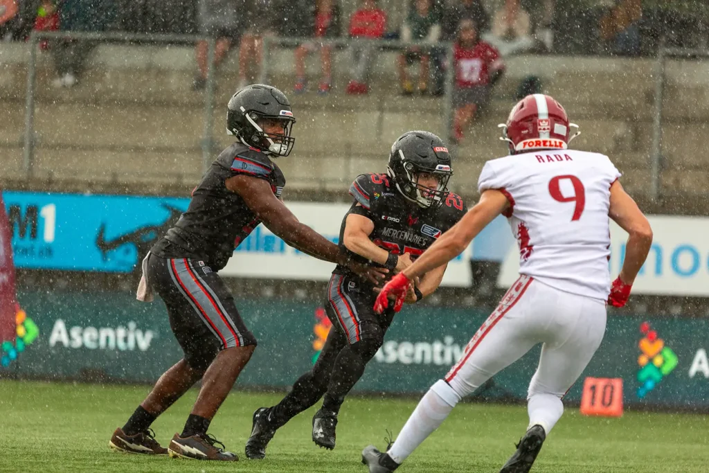 Football players in action during a rainy game, tackling, determination, wet.
