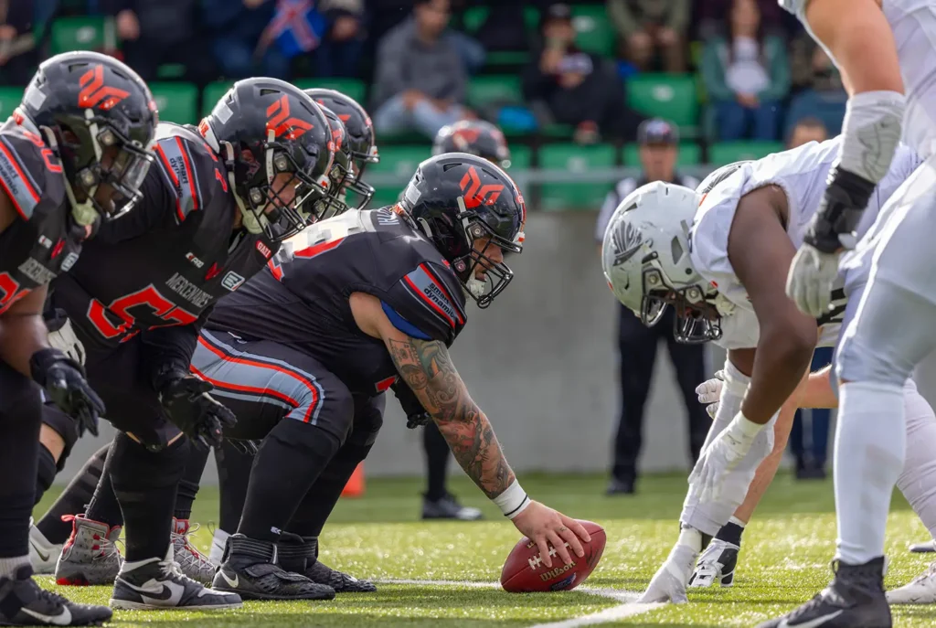 Football players ready for the snap in a game on green field.