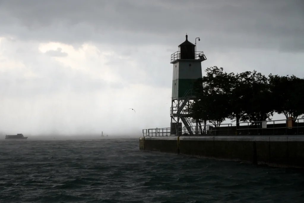 Silhouette of lighthouse and rough seas on Lake Michigan in stormy weather.
