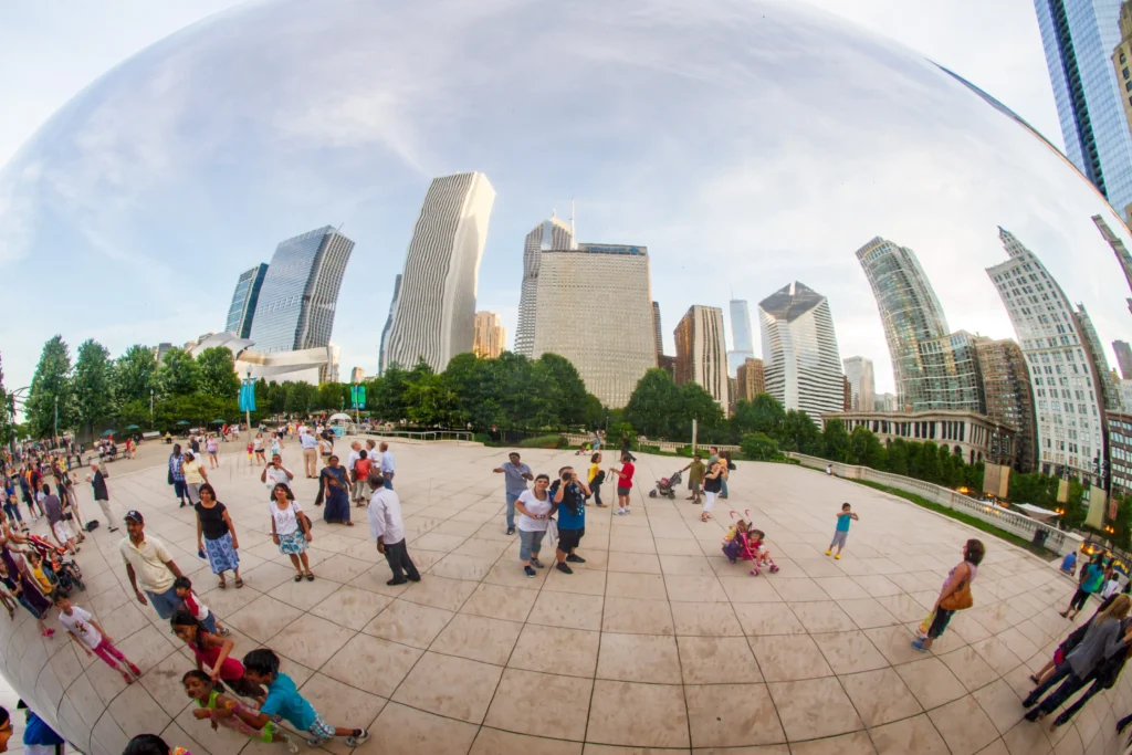Distorted reflections in Chicago's Cloud Gate, people, and city buildings. Fisheye lens.