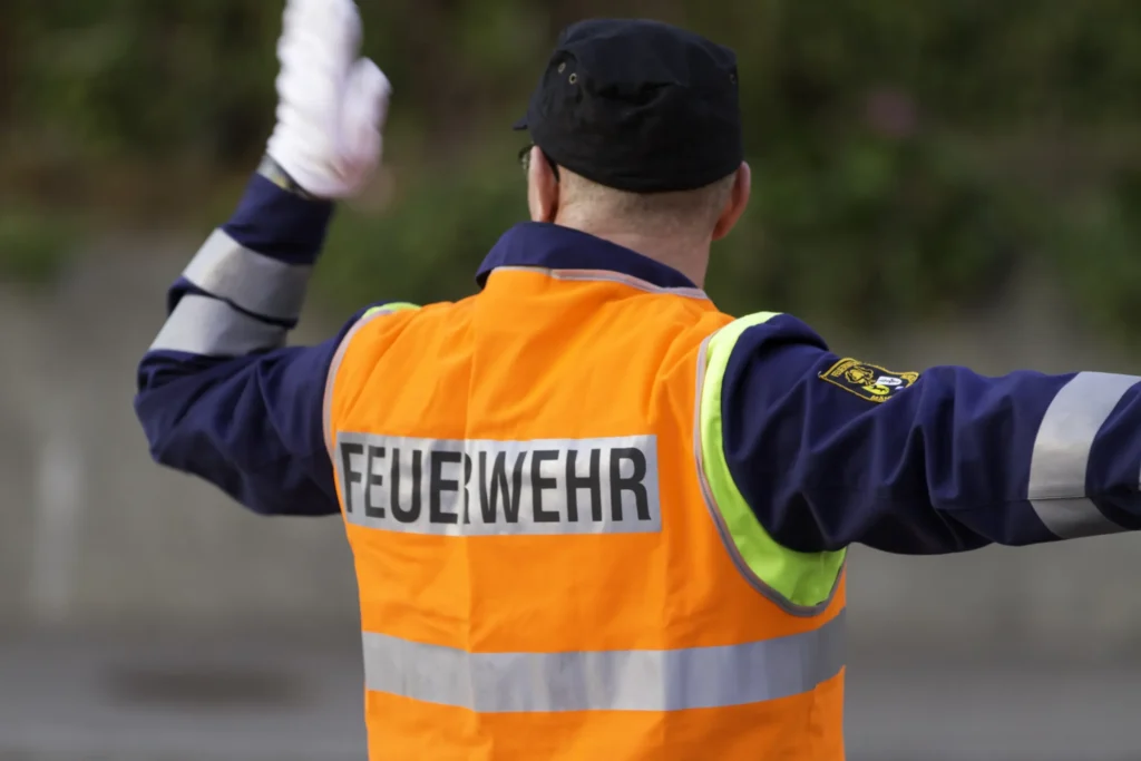 Firefighter in vest directing traffic wearing hat and gloves.