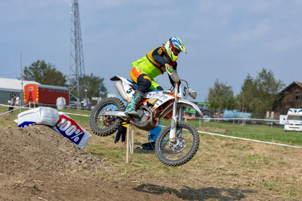 Motocross rider number 5 launching off a dirt jump on a KTM motorcycle