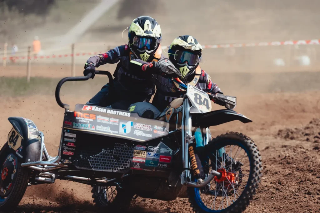 Close-up of sidecar motocross team number 84 Kaser Brothers racing through a dusty dirt track