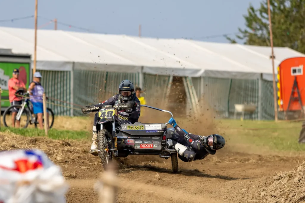 Sidecar motocross team number 18 racing on a dirt track with the passenger leaning out for balance