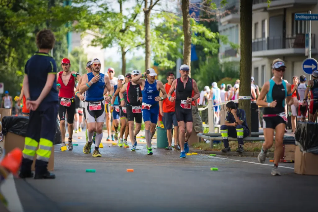 Group of triathletes running along a tree-lined city street during the running leg of a triathlon