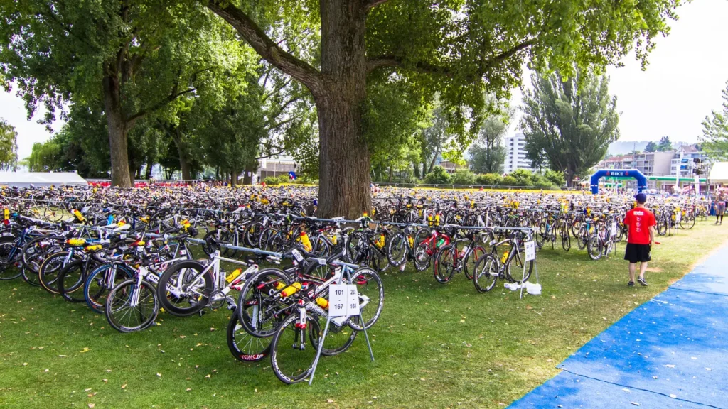 Hundreds of racing bicycles parked in rows at a triathlon transition zone in a park