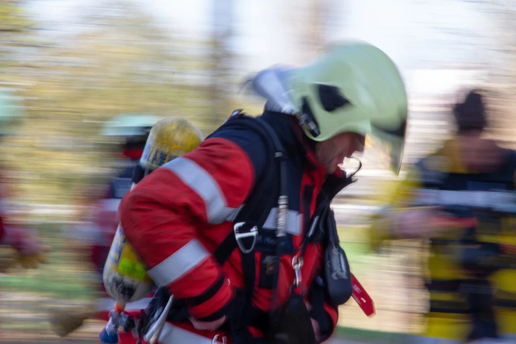 A blurry image of a firefighter rushing into action with full gear.