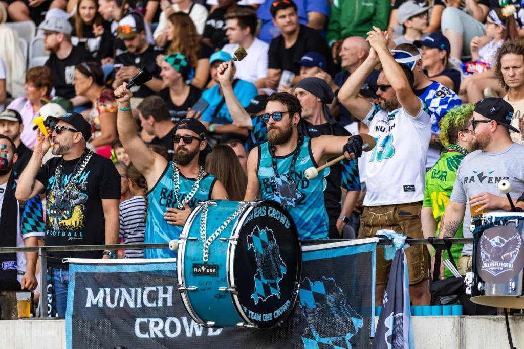 Munich Ravens fans play drums, ring cowbells, and blow horns as they cheer for their team. 29.08.2026, Innsbruck, European Football Alliance, Championship Game, Munich Ravens - Nordic Storm. Foto: PFA/Rico Doninelli